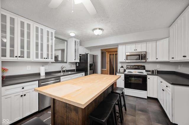 6026 Pennyworth Cir, Indianapolis, IN 46203 - kitchen with stainless steel appliances, a sink, butcher block counters, a breakfast bar area, and a textured ceiling