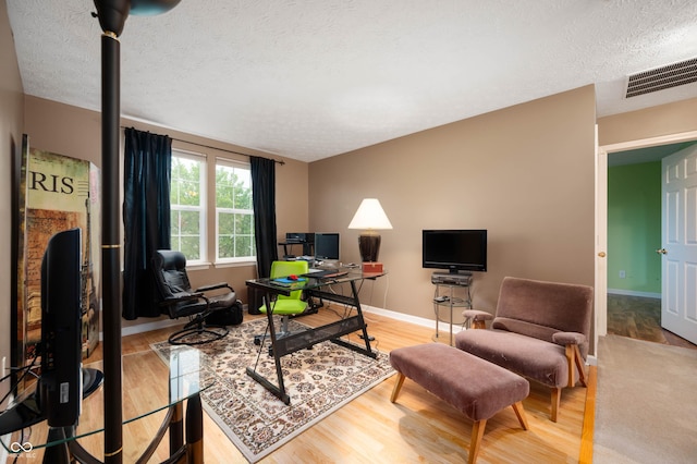 6026 Pennyworth Cir, Indianapolis, IN 46203 - living area with a textured ceiling, a desk, light wood-style floors, and baseboards