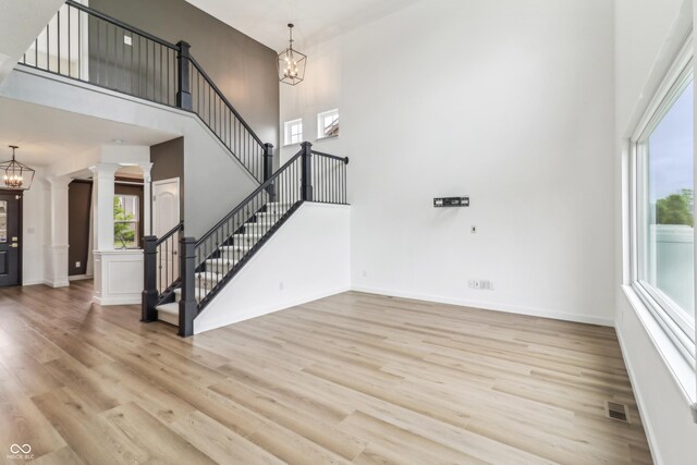 951 Parker Ln, Westfield, IN 46074 - unfurnished living room with a towering ceiling, a chandelier, wood finished floors, stairway, and decorative columns
