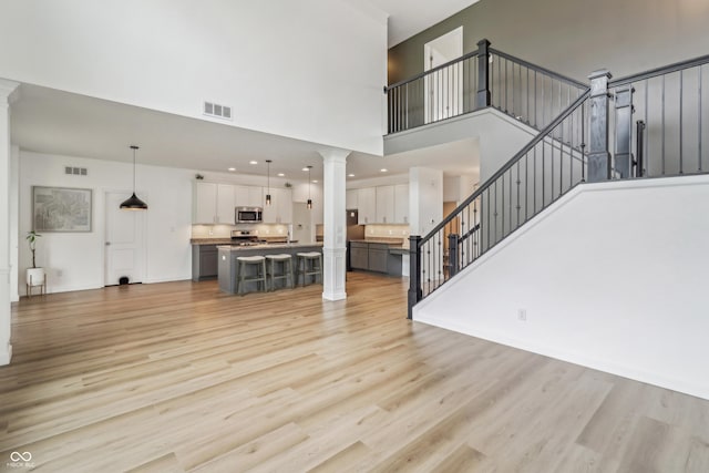 951 Parker Ln, Westfield, IN 46074 - unfurnished living room featuring ornate columns, a high ceiling, light wood-style floors, and stairs