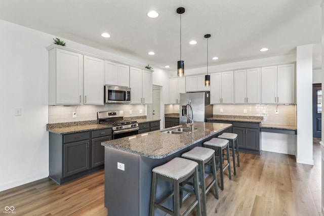 951 Parker Ln, Westfield, IN 46074 - kitchen featuring appliances with stainless steel finishes, a sink, a breakfast bar area, backsplash, and a center island with sink
