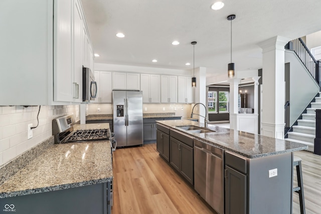 951 Parker Ln, Westfield, IN 46074 - kitchen with stainless steel appliances, a sink, decorative columns, white cabinets, and light wood-type flooring