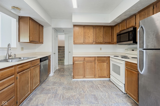 9572 Maple Way, Indianapolis, IN 46268 - kitchen featuring appliances with stainless steel finishes, a sink, brown cabinetry, light countertops, and light stone finish flooring