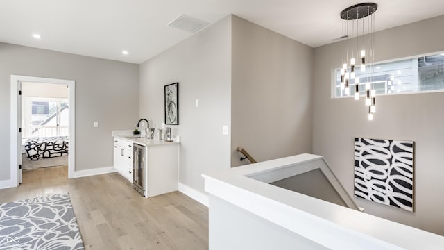 43 N Walcott St, Indianapolis, IN 46201 - hallway featuring an upstairs landing, beverage cooler, a sink, light wood-style floors, and baseboards