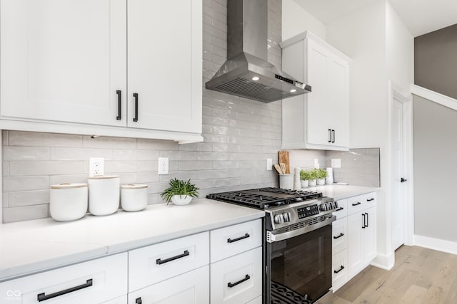 43 N Walcott St, Indianapolis, IN 46201 - kitchen with stainless steel gas stove, wall chimney range hood, light wood-style floors, tasteful backsplash, and white cabinetry