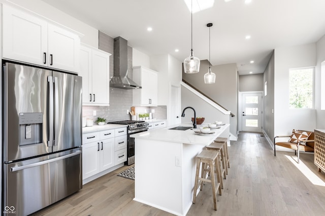 43 N Walcott St, Indianapolis, IN 46201 - kitchen with stainless steel appliances, wall chimney range hood, a sink, light wood finished floors, and tasteful backsplash