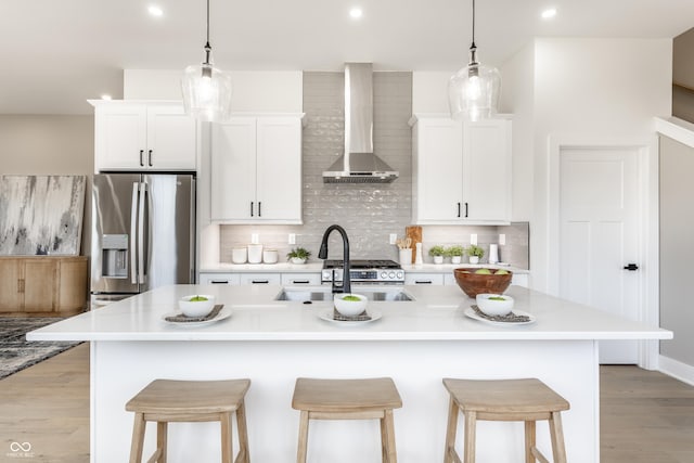 43 N Walcott St, Indianapolis, IN 46201 - kitchen featuring stainless steel appliances, wall chimney exhaust hood, an island with sink, light wood-style flooring, and white cabinets