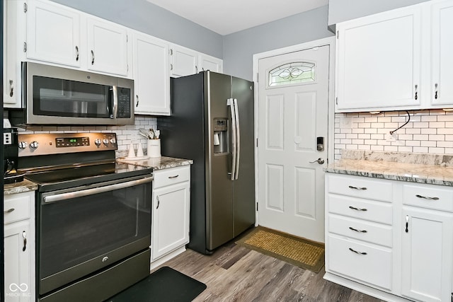 1236 Central Ave, Indianapolis, IN 46202 - kitchen with appliances with stainless steel finishes, tasteful backsplash, white cabinetry, and wood finished floors
