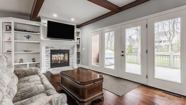 living area featuring beam ceiling, healthy amount of natural light, dark wood-style floors, a multi sided fireplace, and recessed lighting
