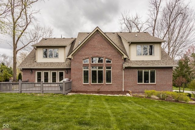 back of house with a shingled roof, brick siding, a yard, and a deck