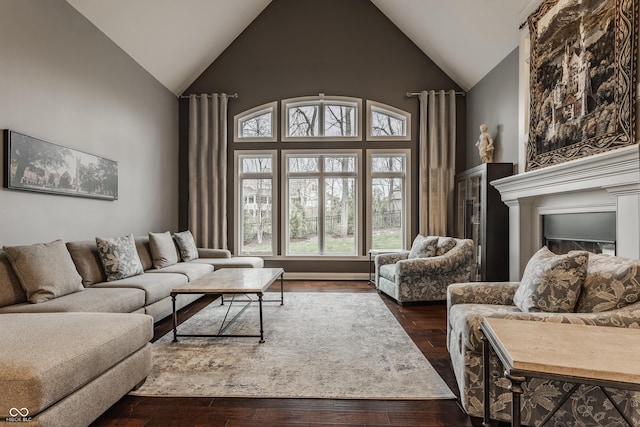 living room featuring dark wood-style flooring, high vaulted ceiling, and a fireplace
