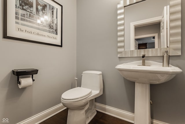 bathroom with baseboards, toilet, and wood finished floors