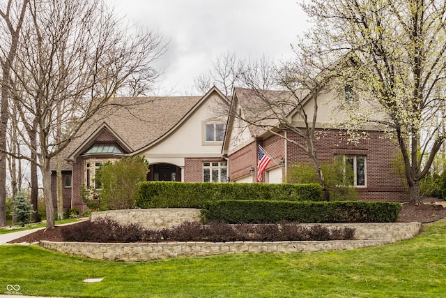 tudor house featuring brick siding, stucco siding, and a front yard