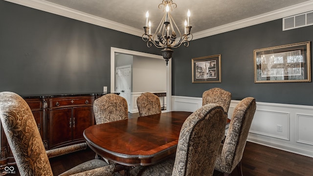 dining space with a chandelier, dark wood-style floors, a wainscoted wall, crown molding, and a decorative wall