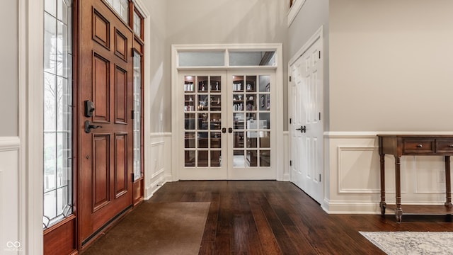 entrance foyer with a decorative wall, dark wood-style floors, french doors, and wainscoting