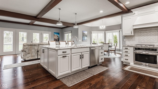 kitchen with stainless steel appliances, beamed ceiling, a sink, white cabinetry, and dark wood-style flooring