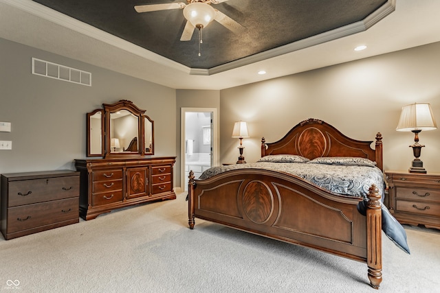 bedroom featuring a tray ceiling, light colored carpet, recessed lighting, ornamental molding, and connected bathroom