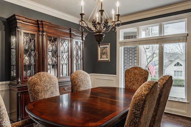 dining area with a chandelier, ornamental molding, a wainscoted wall, a decorative wall, and dark wood finished floors
