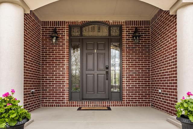 entrance to property with stucco siding, brick siding, and a porch