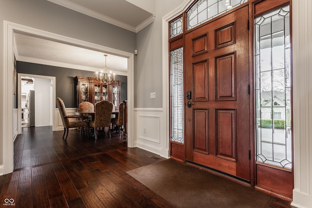 foyer featuring a chandelier, dark wood-style flooring, ornamental molding, and wainscoting
