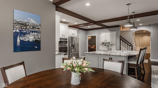 dining area featuring arched walkways, dark wood-style floors, recessed lighting, beam ceiling, and baseboards