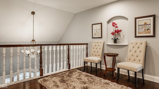 sitting room with baseboards, a chandelier, hardwood / wood-style floors, and lofted ceiling