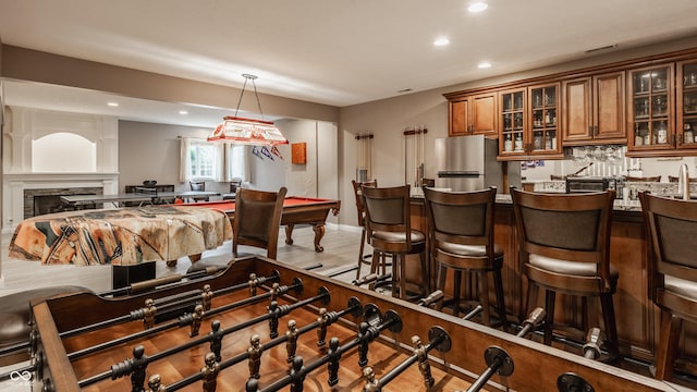 indoor wet bar featuring freestanding refrigerator, recessed lighting, decorative light fixtures, and a fireplace