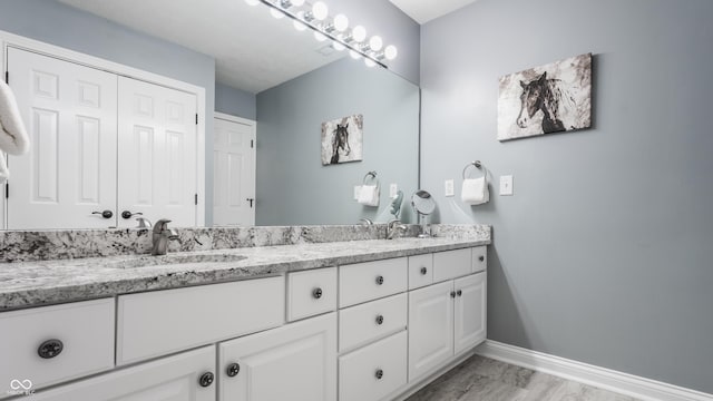 bathroom featuring baseboards and double vanity
