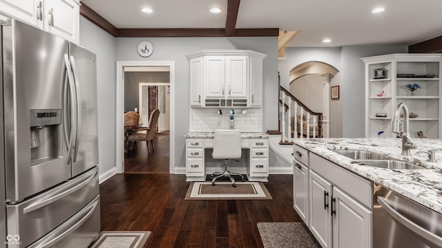 kitchen featuring appliances with stainless steel finishes, a sink, dark wood-style flooring, decorative backsplash, and white cabinetry