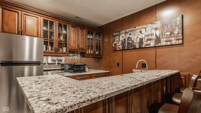 indoor wet bar with freestanding refrigerator and a decorative wall