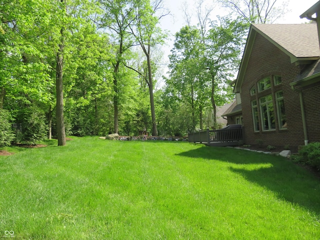 view of green lawn featuring a deck