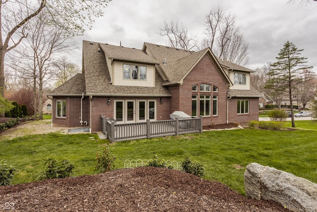 rear view of property featuring brick siding, a yard, and a shingled roof