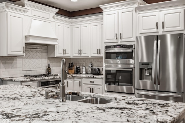 kitchen featuring appliances with stainless steel finishes, a sink, white cabinetry, light stone countertops, and recessed lighting