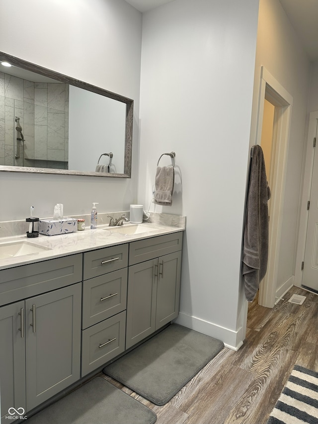 951 N Maiellen Dr, Greenfield, IN 46140 - bathroom featuring wood finished floors, double vanity, baseboards, and a tile shower