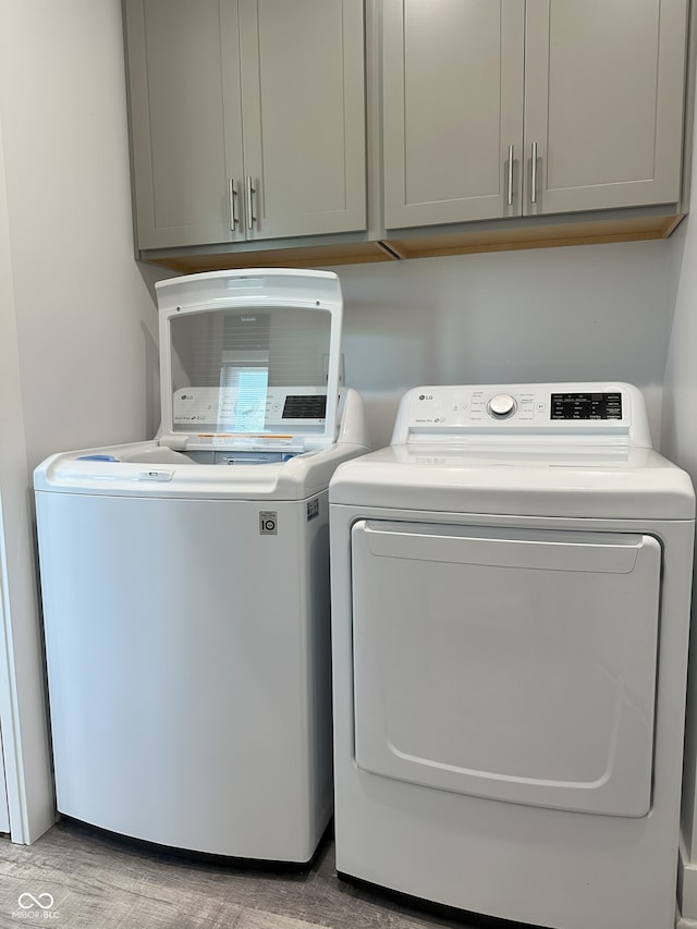 951 N Maiellen Dr, Greenfield, IN 46140 - laundry area featuring washer and dryer, cabinet space, and wood finished floors