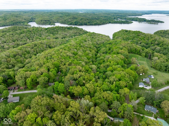 drone / aerial view of a nearby body of water and a heavily wooded area