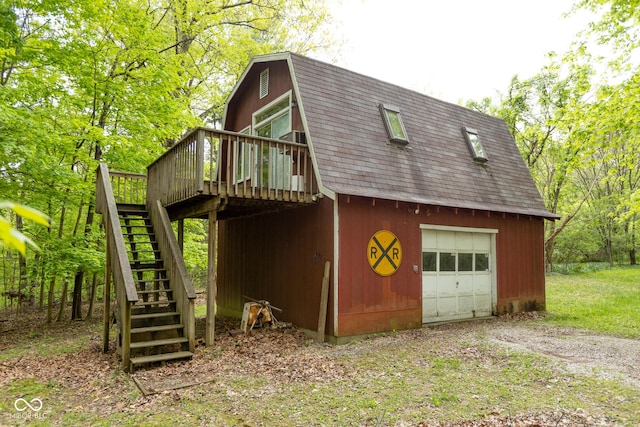 view of side of home featuring stairs, a gambrel roof, a wooden deck, roof with shingles, and dirt driveway