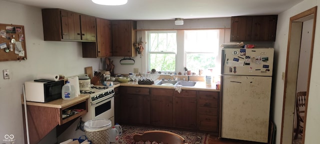 kitchen featuring white appliances, a sink, and light countertops