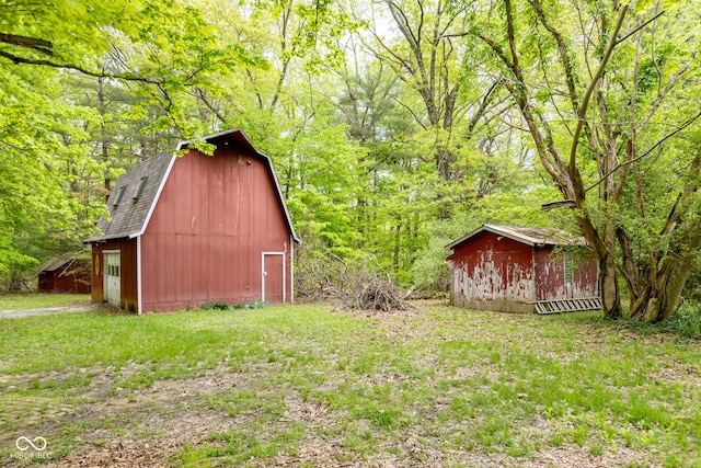 view of yard with a barn, an outbuilding, a storage shed, a forest view, and a garage