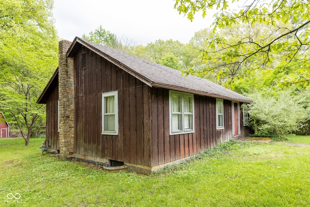 view of home's exterior featuring a chimney, a yard, and an outdoor structure