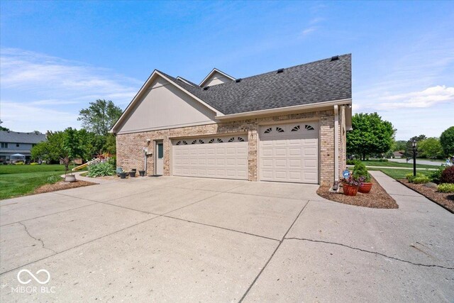 12082 Old Stone Dr, Indianapolis, IN 46236 - view of side of home with brick siding, concrete driveway, a garage, and roof with shingles