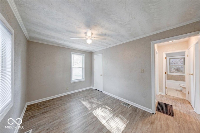1852 N Warman Ave, Indianapolis, IN 46222 - unfurnished bedroom featuring ornamental molding, wood finished floors, a textured wall, a textured ceiling, and a ceiling fan
