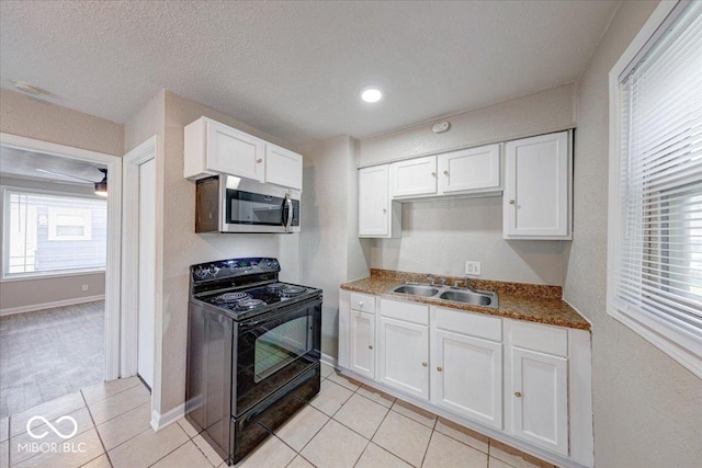 1852 N Warman Ave, Indianapolis, IN 46222 - kitchen featuring black range with electric cooktop, stainless steel microwave, light tile patterned flooring, and white cabinets