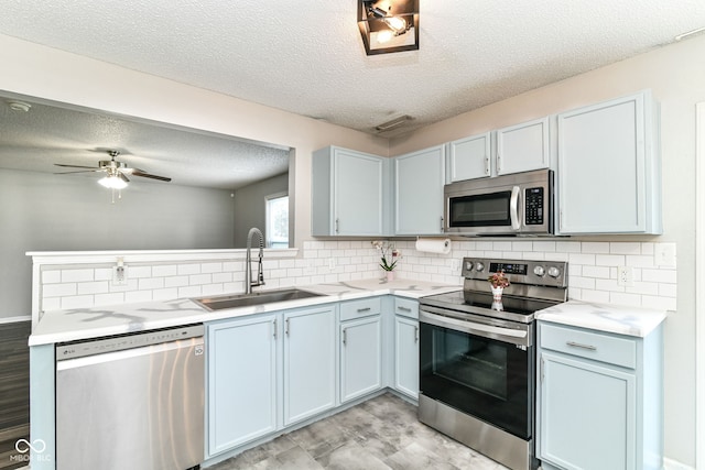 9676 W Constellation Dr, Pendleton, IN 46064 - kitchen with appliances with stainless steel finishes, a sink, a textured ceiling, backsplash, and light countertops