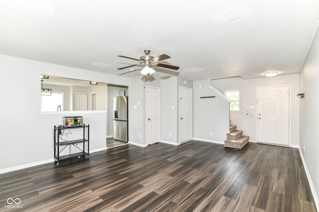 9676 W Constellation Dr, Pendleton, IN 46064 - unfurnished living room featuring dark wood-type flooring, ceiling fan, stairs, a textured ceiling, and baseboards