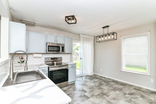 9676 W Constellation Dr, Pendleton, IN 46064 - kitchen with appliances with stainless steel finishes, a sink, light countertops, tasteful backsplash, and a textured ceiling