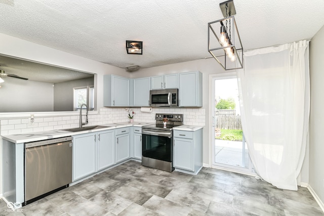 9676 W Constellation Dr, Pendleton, IN 46064 - kitchen featuring stainless steel appliances, a sink, light countertops, tasteful backsplash, and a textured ceiling