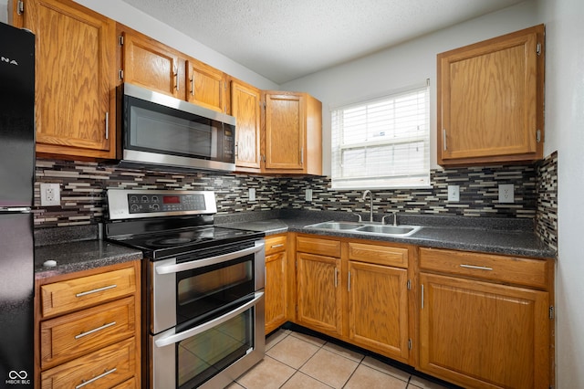 6715 Wandering Way, Indianapolis, IN 46241 - kitchen featuring stainless steel appliances, a sink, dark countertops, backsplash, and light tile patterned floors