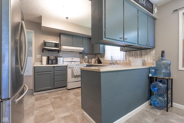 6310 E County Road 200 S, Butlerville, IN 47223 - kitchen with appliances with stainless steel finishes, a peninsula, under cabinet range hood, light countertops, and gray cabinets