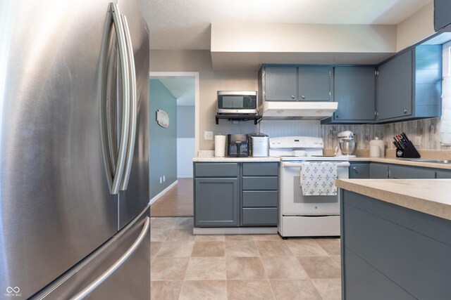 6310 E County Road 200 S, Butlerville, IN 47223 - kitchen featuring stainless steel appliances, under cabinet range hood, light countertops, gray cabinetry, and decorative backsplash
